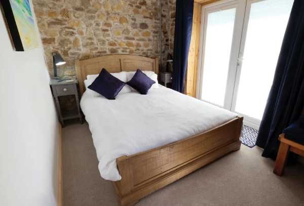 The Pendragon - cozy bedroom with stone feature wall and wooden bed frame